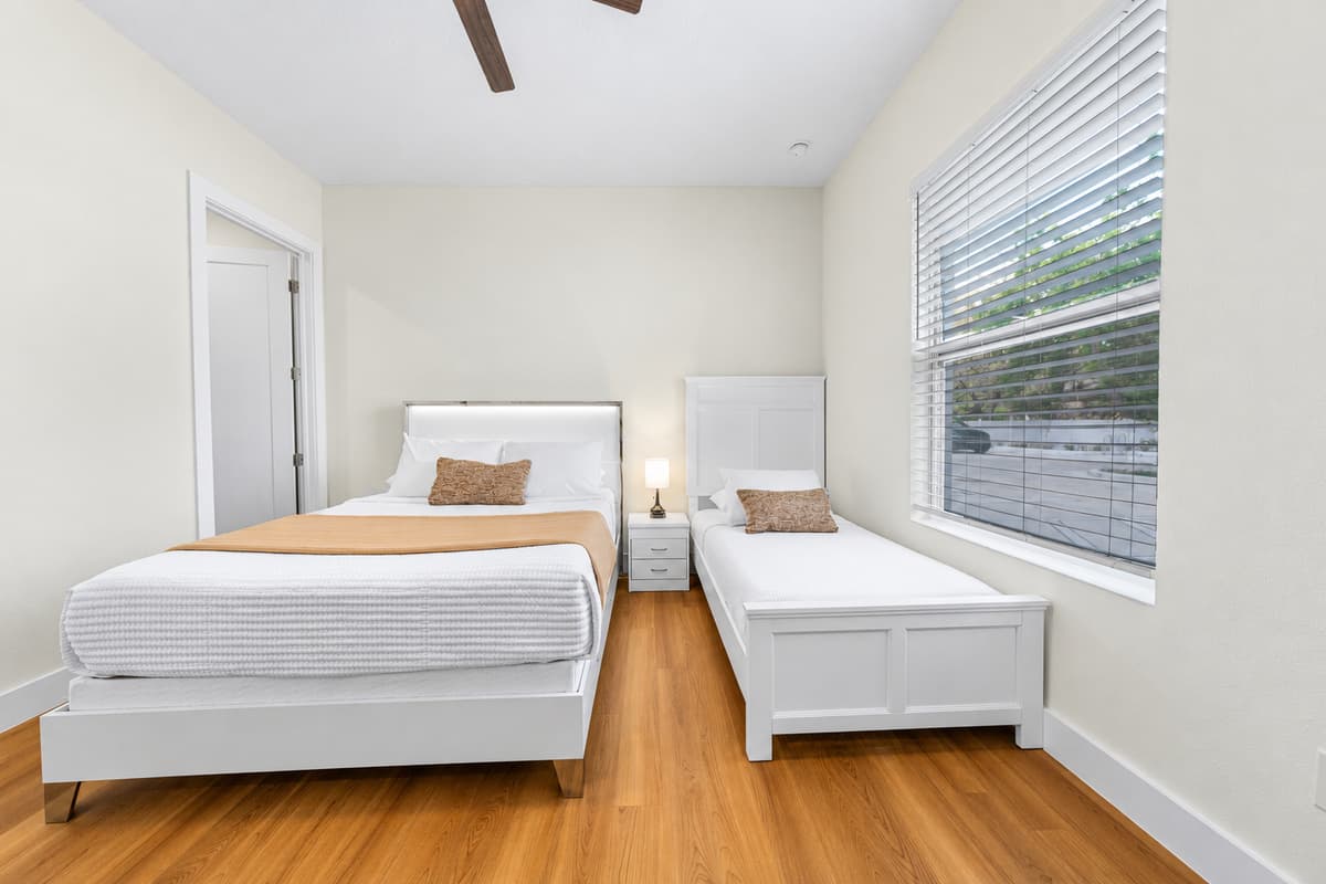 Bedroom 2: queen and twin beds, private en-suite bathroom, desk, TV, and closet; sleeps 3.