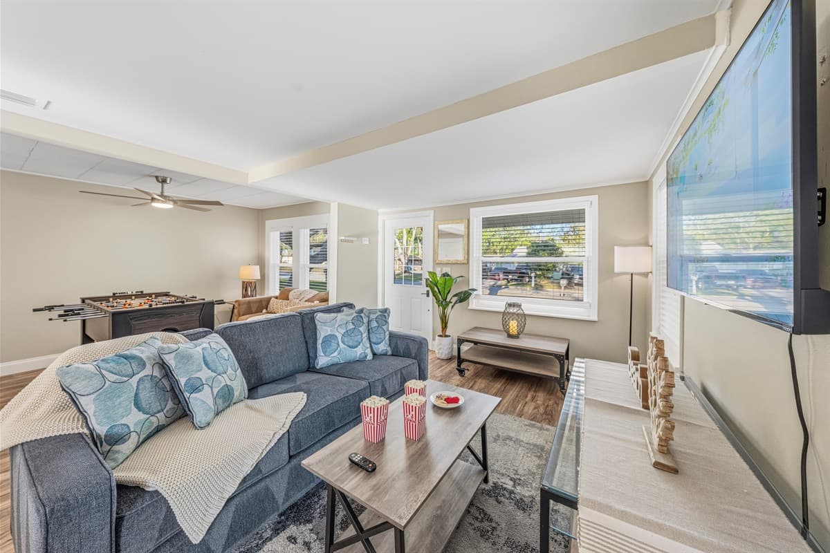 Bright and cozy living room with comfortable seating, large TV, and a fun foosball table for entertainment.