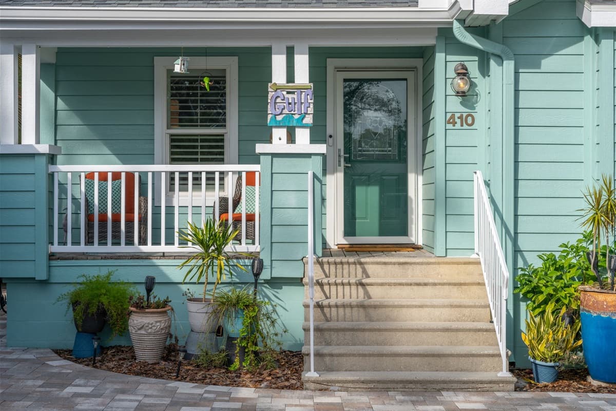 Charming curb appeal includes a welcoming porch, vibrant potted plants, and refreshing coastal architecture.