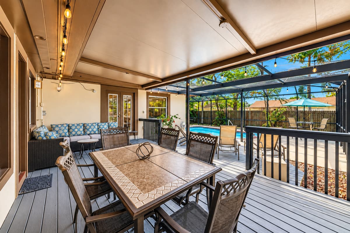 Large outdoor entertaining space with dining table, lounge seating, and screened enclosure.