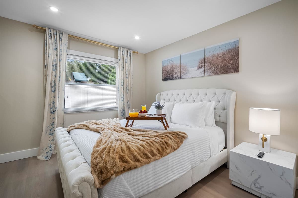 This cozy queen bedroom offers a plush tufted bed, soft linens, and soothing neutral tones for a peaceful night’s rest.