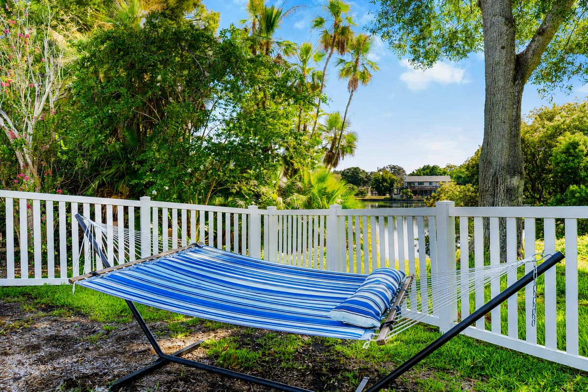 A hammock under the oaks, white fence around it. The quietest twenty minutes of your day.