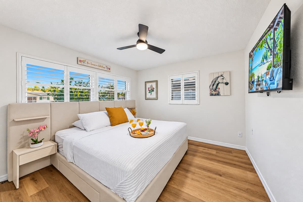 Spacious king bedroom with TV, soft lighting, and a comfortable layout for restful nights 
Tray and food setup shown are for staging purposes only and are not included.