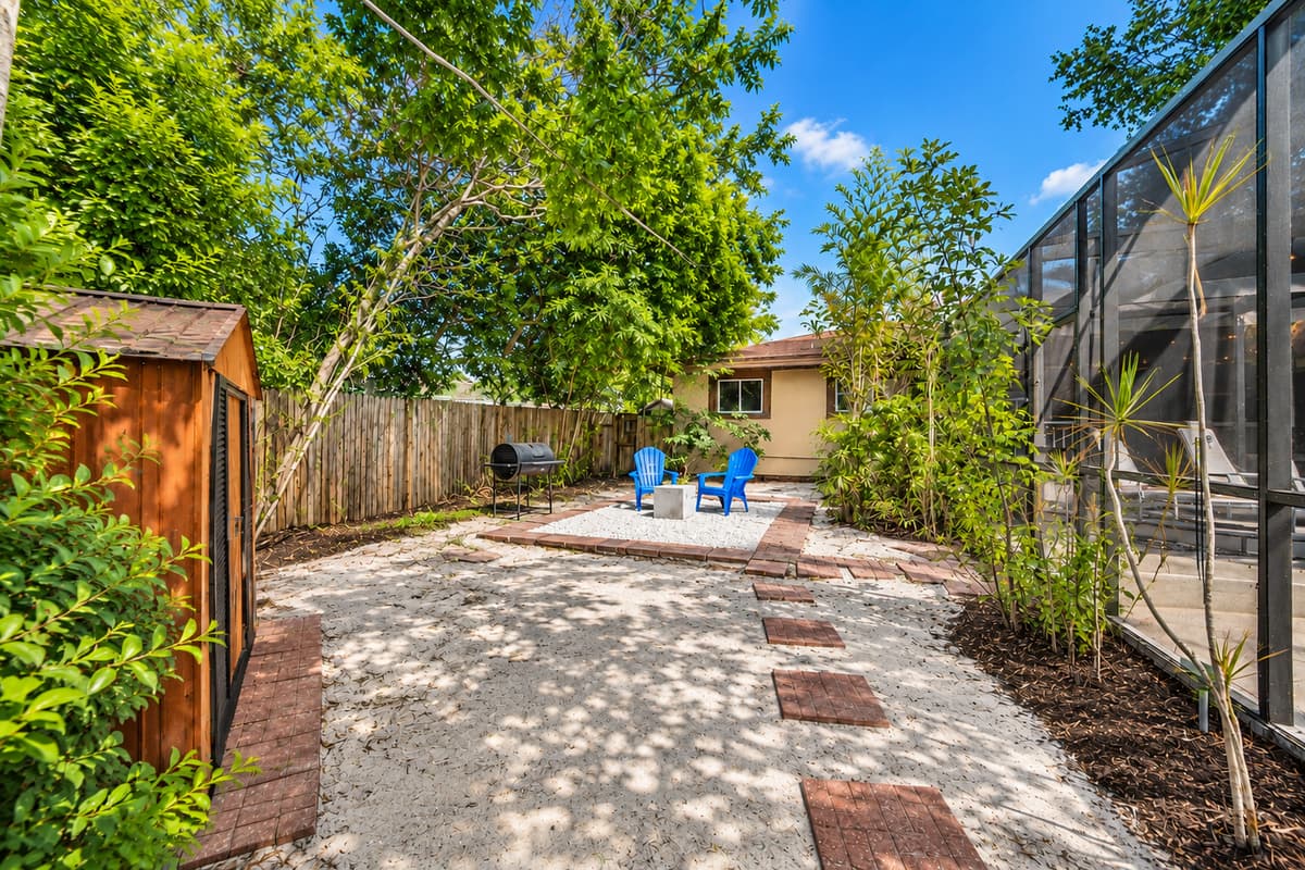 Peaceful garden-style backyard with shaded walking paths, outdoor seating, and private fenced surroundings.