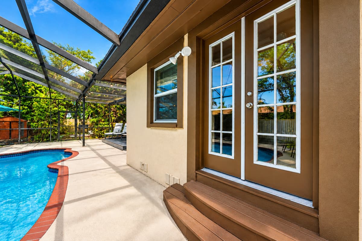 Cozy poolside entrance featuring French doors and a peaceful screened enclosure.