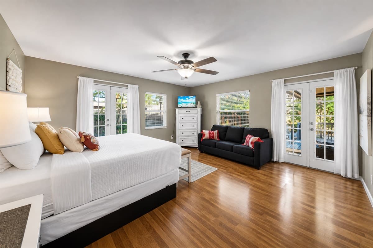 Expansive master bedroom with a king bed, sitting area, and oversized windows for natural sunlight.
