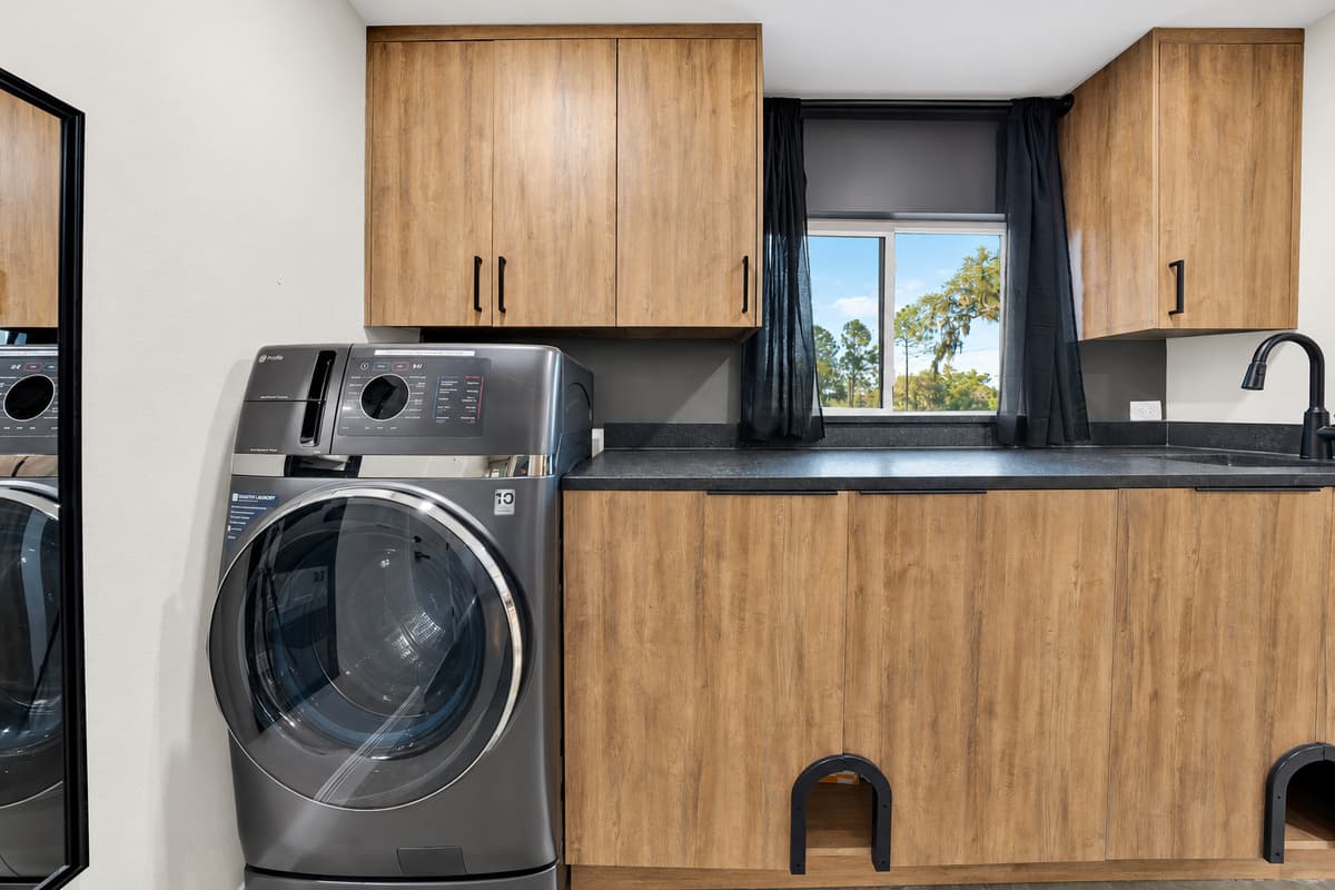 Sandy towels handled the same afternoon. Full-size front-loading machines with a window above and storage all around — the amenity that makes a long stay feel effortless instead of complicated.