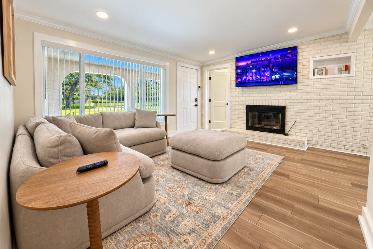 Front living room with sectional seating, TV and fireplace feature.