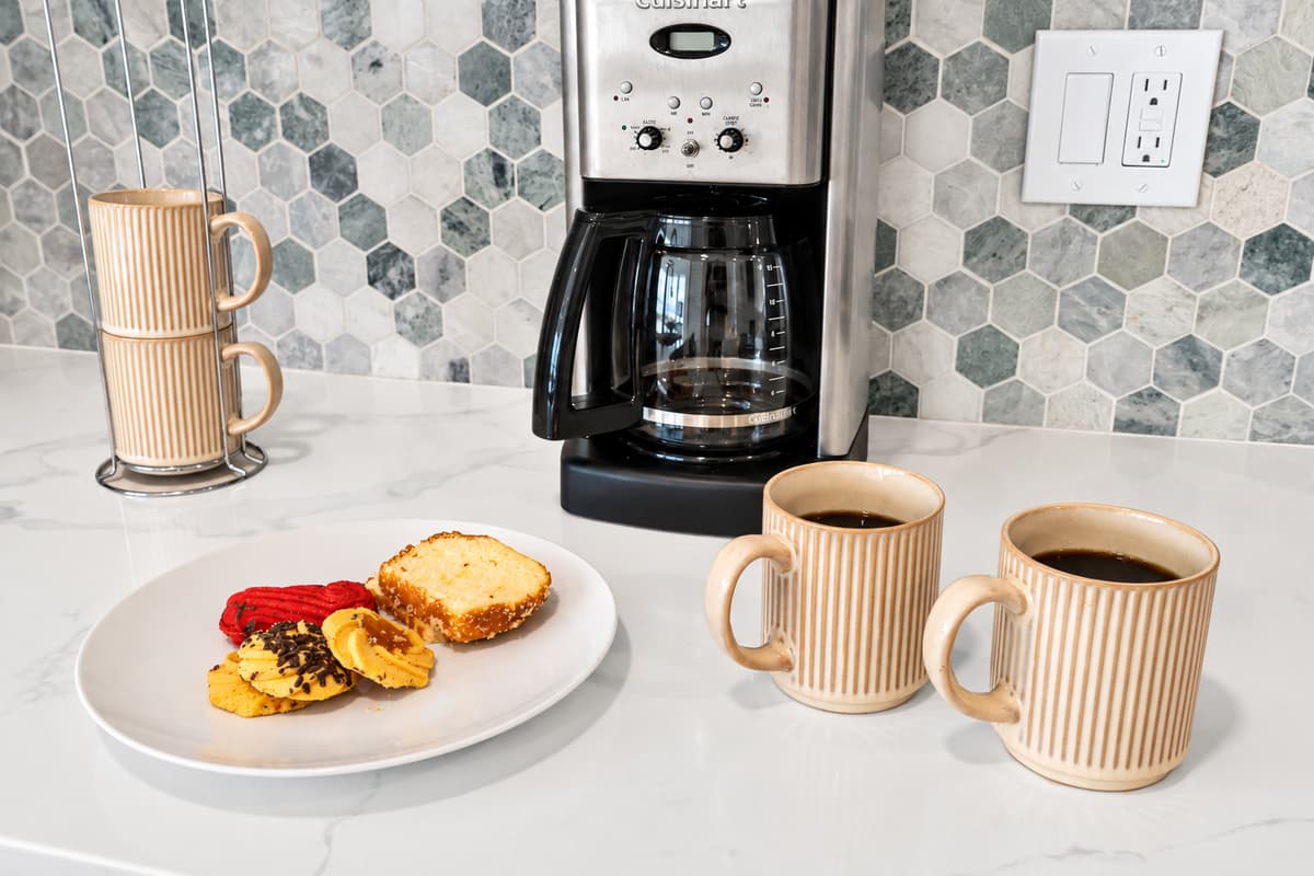 Coffee first, then the bay. A drip coffee maker, ceramic mugs and a pastry plate on the counter. Mornings here start slow and taste good.