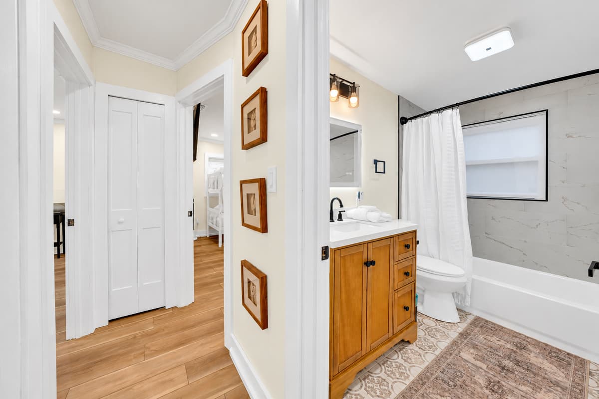 Bathroom 2 with a tub and shower. A wood vanity, soft rug and tub and shower combo. Close to the bedrooms and easy for families.