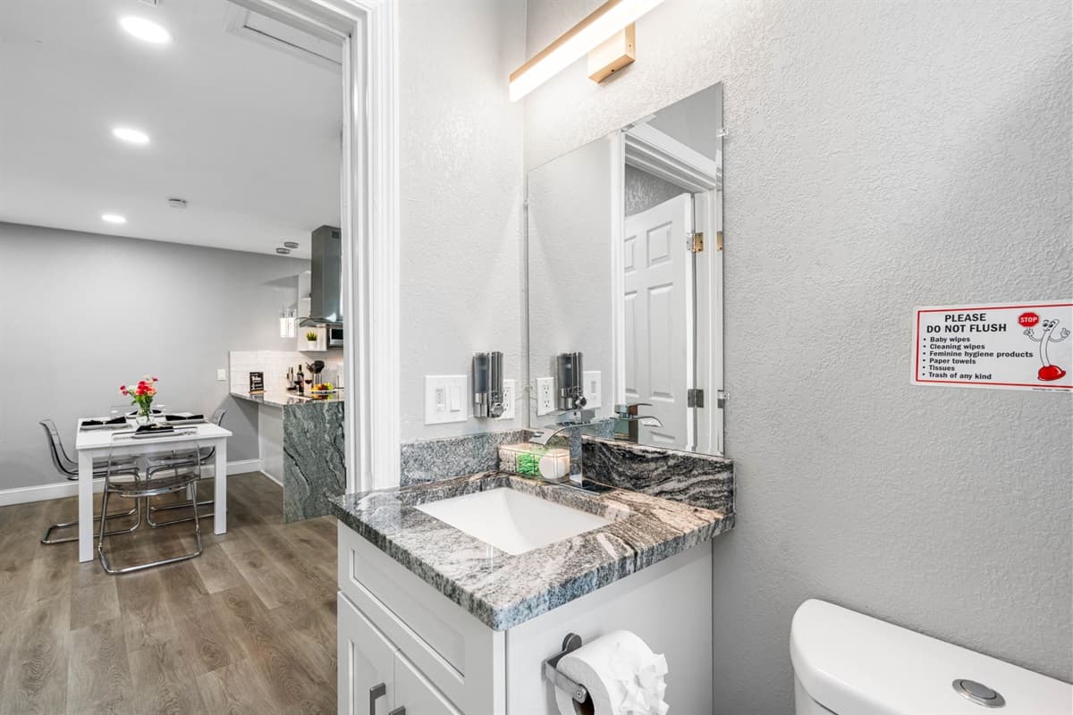 The vanity, topped with a polished marble countertop, provides ample space for all your toiletries and features a large mirror that enhances the room's brightness and spaciousness.