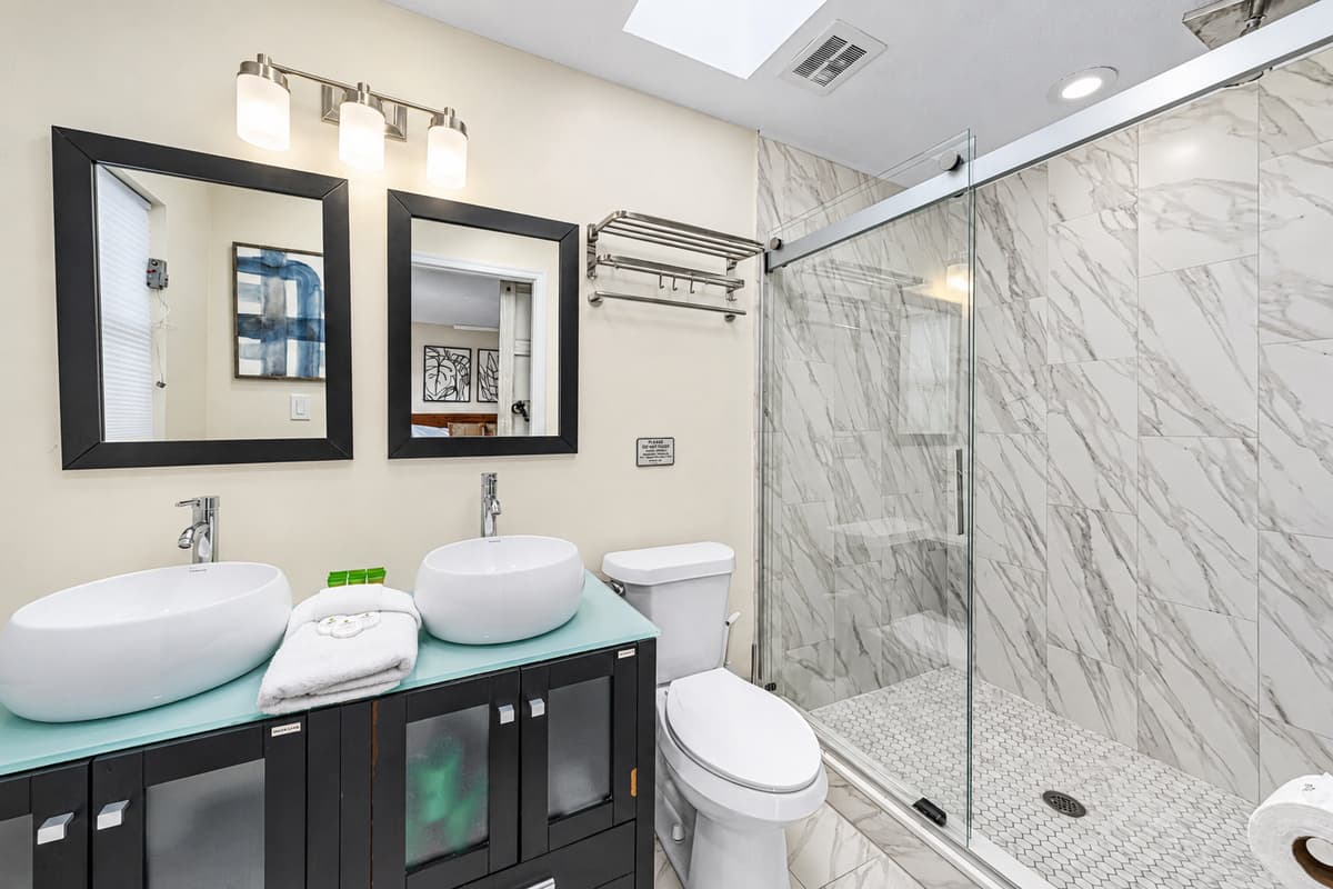 Modern bathroom with dual vessel sinks and a luxurious walk-in marble shower.