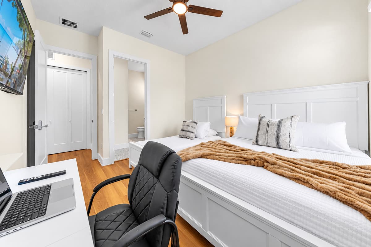 Cozy bedroom with plush bedding, desk setup, and relaxing ambiance.