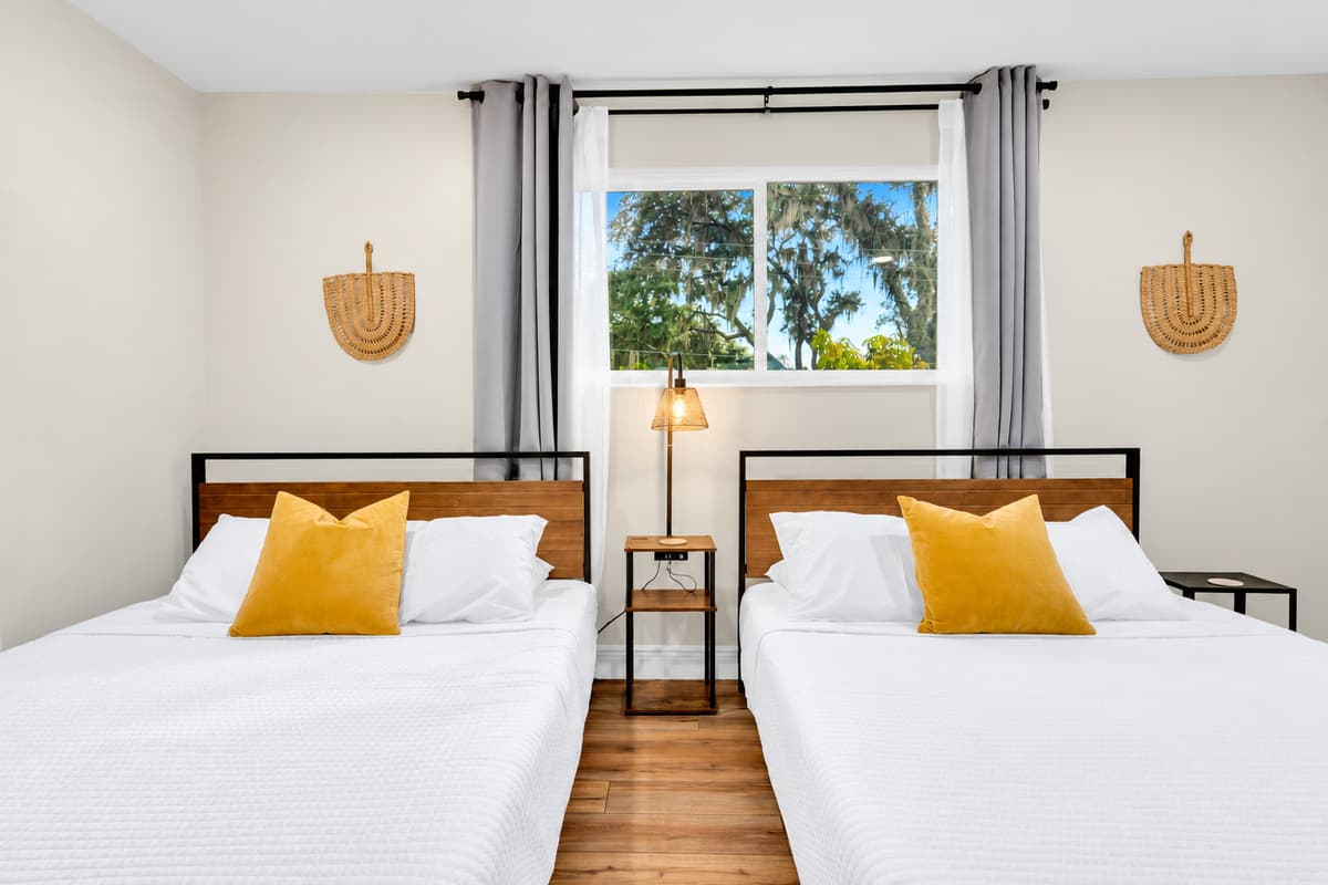 Two beds, deep sleep, garden outside. Warm sconce lighting, soft linens and a window onto the trees — the quiet corner of the estate where the noise from the water never reaches.