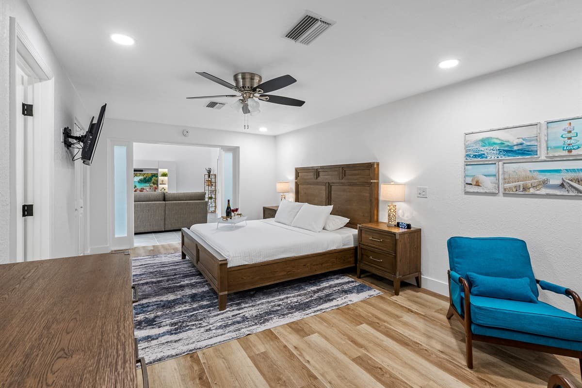 Unwind in style in this spacious primary suite, featuring a plush king bed, elegant wood furnishings, and a cozy seating nook—your private retreat within the retreat.
