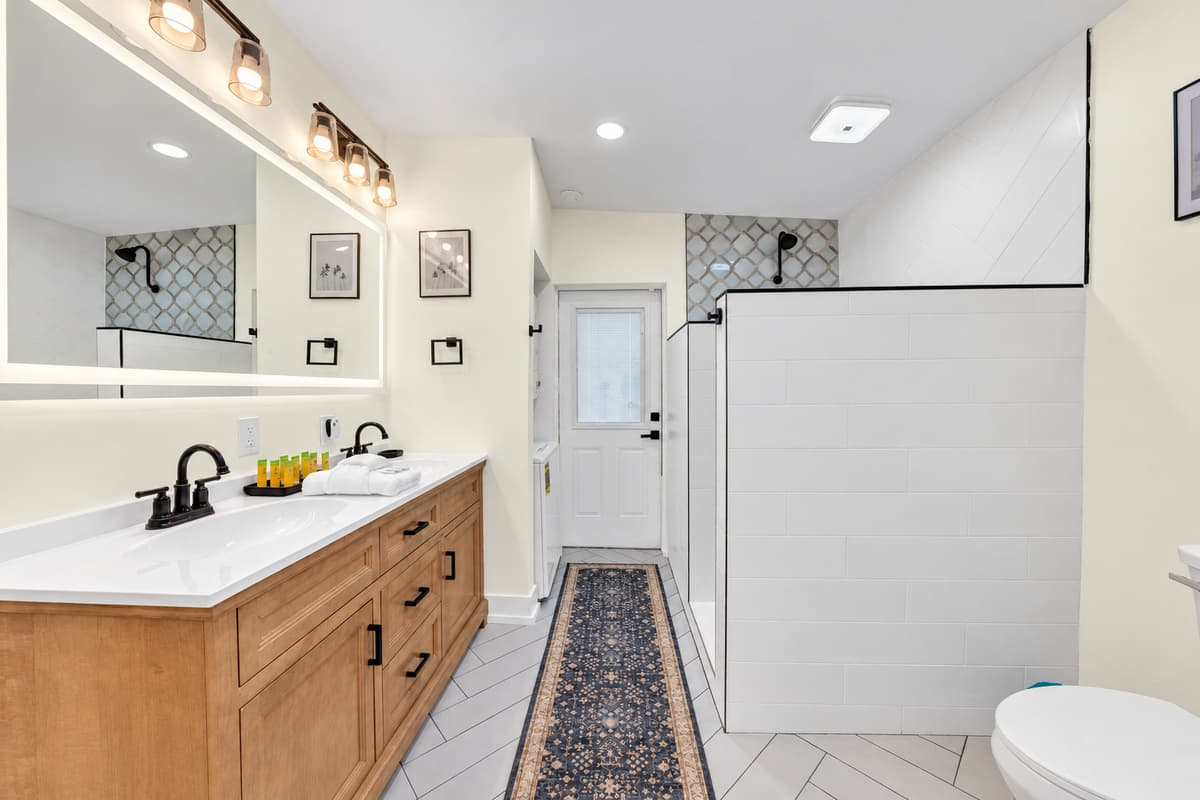 Double vanity and an open walk-in shower. Bathroom 1 has two sinks, a lighted mirror and a tiled walk-in shower. Plenty of space for two people getting ready at once.