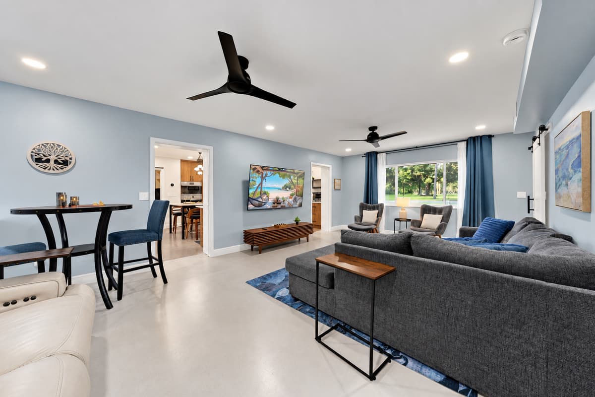 Sofa, dining table and the pool just outside. Open-plan living where the group naturally collects — eat, sprawl, watch something, and step straight out when the water calls.