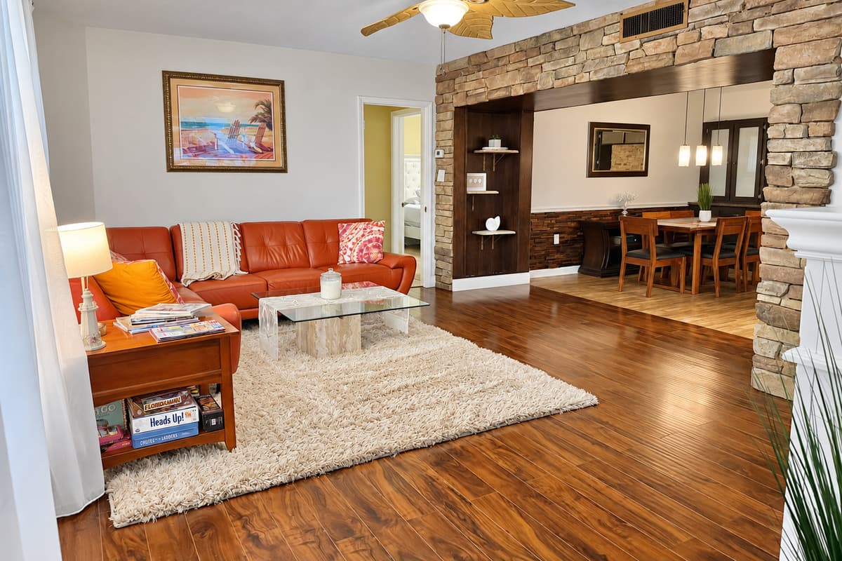 With bold burnt-orange seating, glass-top coffee table, and a shag rug underfoot, this space blends retro flair with modern comfort.