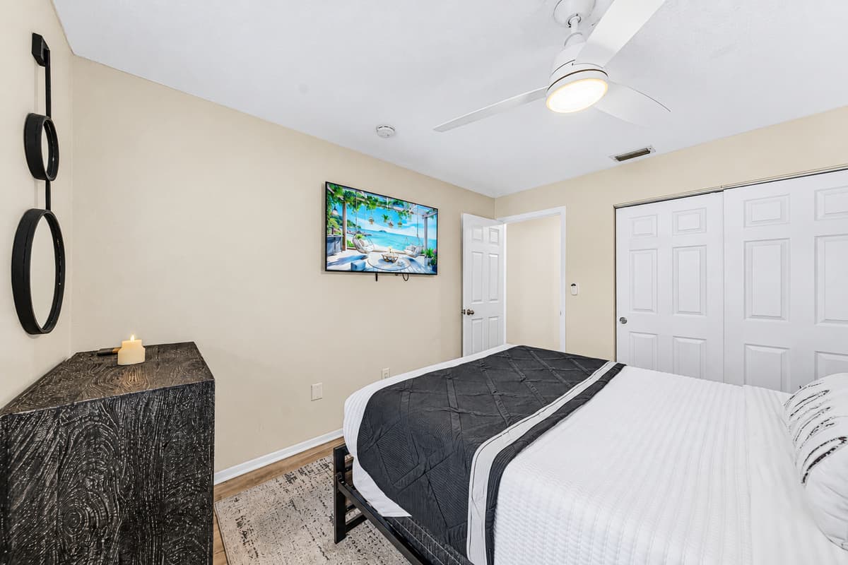 Spacious guest bedroom featuring a queen bed, Smart TV, and ample storage.