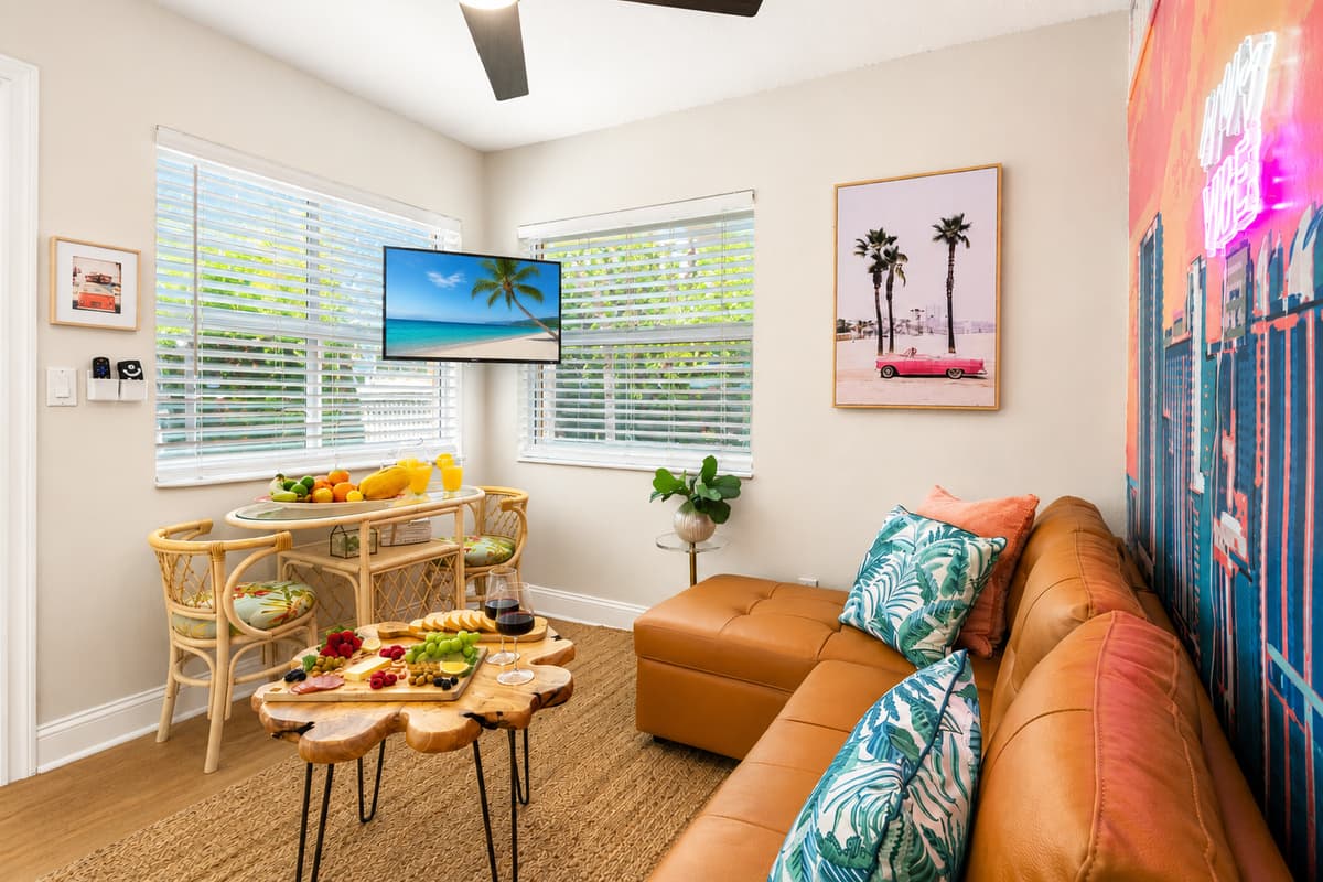 A bright and inviting living room featuring comfortable seating, Smart TV, dining area, and tropical-inspired décor just minutes from the beach.