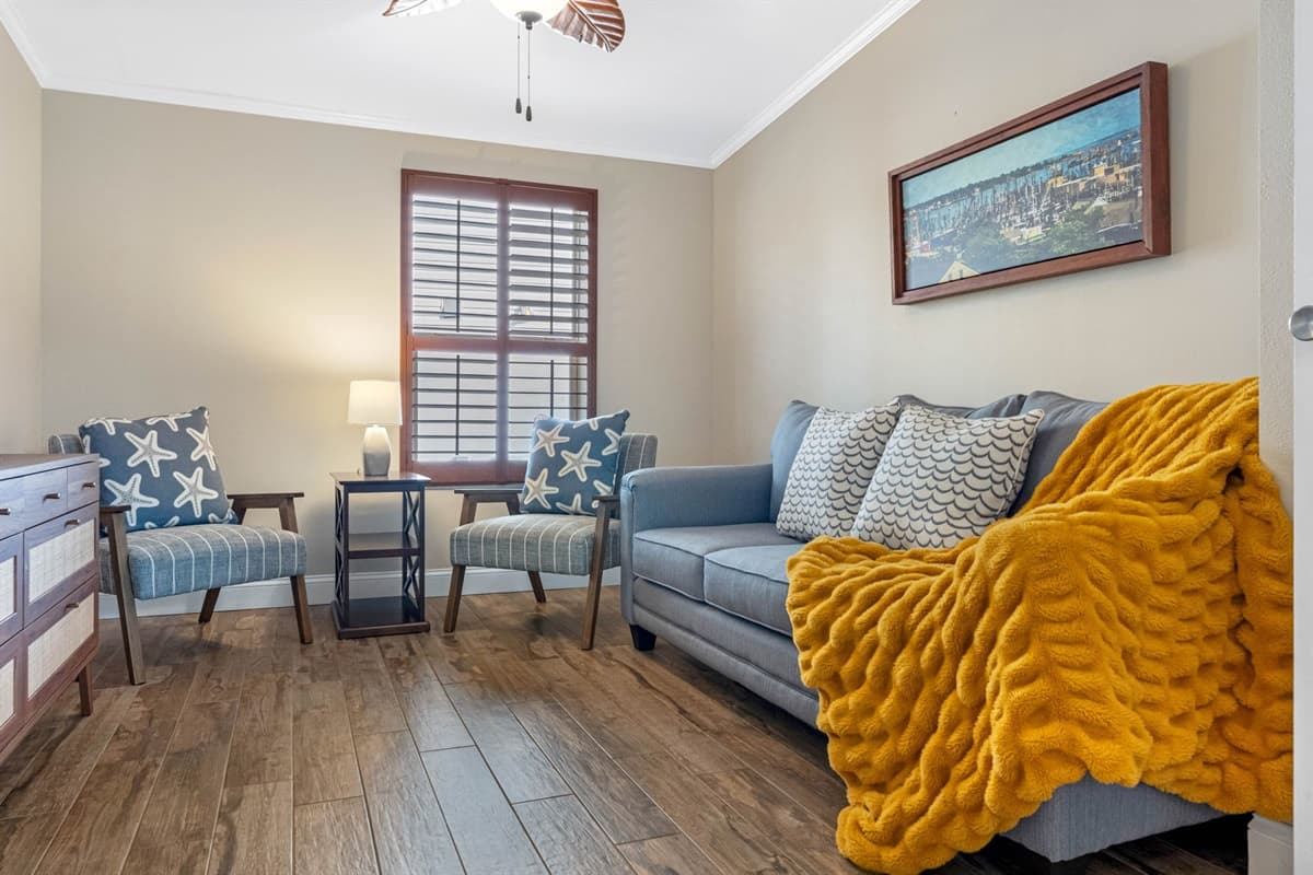 This cozy bedroom features a stylish pullout sofa bed, offering a comfortable sleeping option with flexible use during the day. Coastal décor, warm wood floors, and soft lighting create a relaxing and inviting retreat.