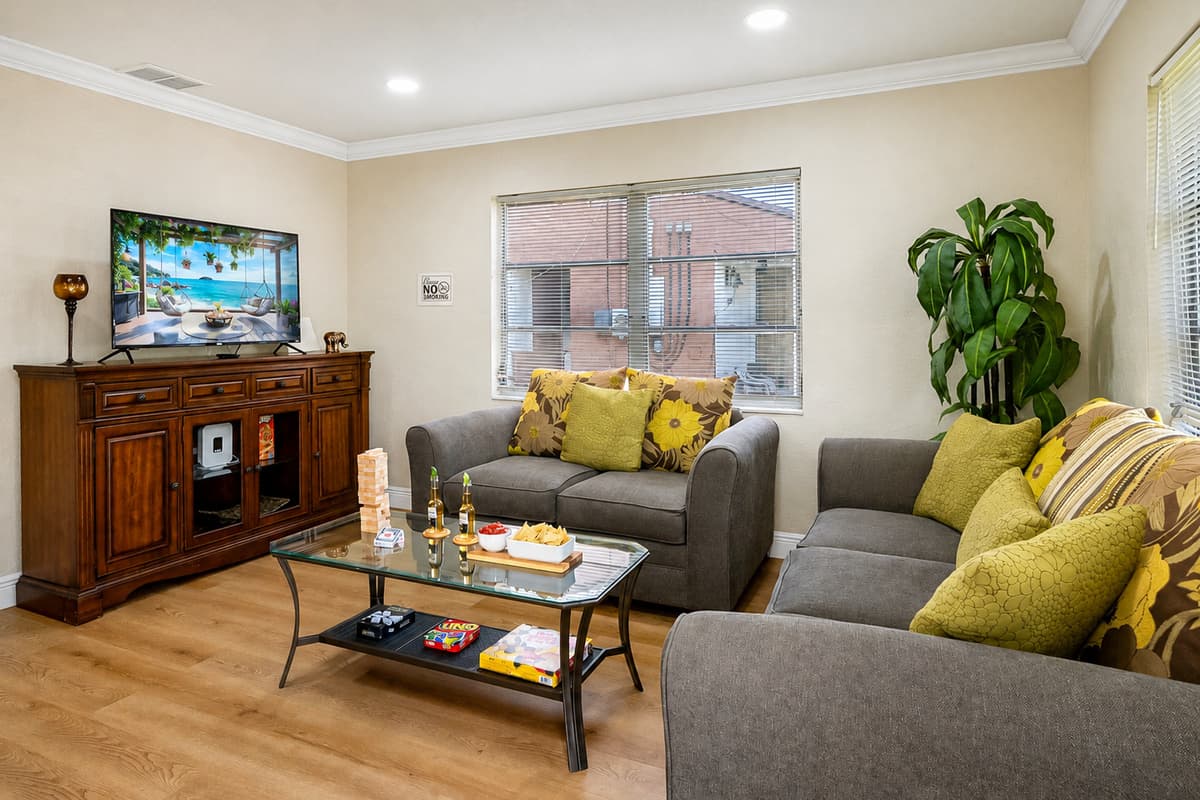 At the center of the room are two plush, soft grey couches, perfectly positioned to encourage relaxation, conversation, or a laid-back movie night.