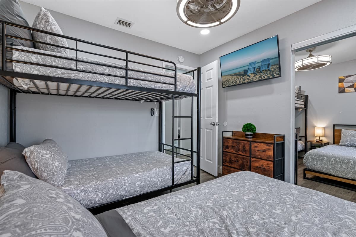 Beautiful bedroom with single bunk bed, queen-sized bed, drawers for storage, and smart TV. Ideal room for a family with kids or a group of friends.