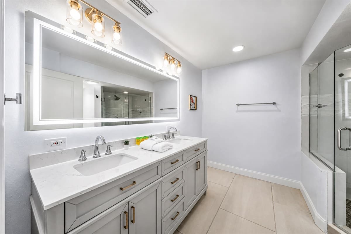 Luxurious double-sink vanity with oversized mirror and sleek modern lighting.