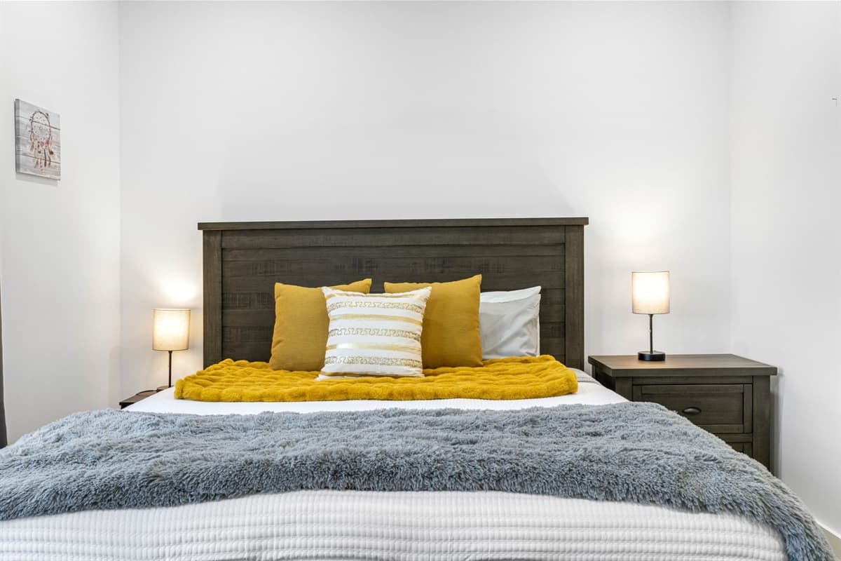 The bedding is complemented by stylish throw pillows and a beautifully coordinated bedspread, adding a touch of elegance to the room.
