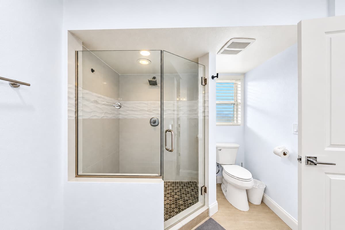 Private walk-in shower with glass enclosure and bright natural lighting.