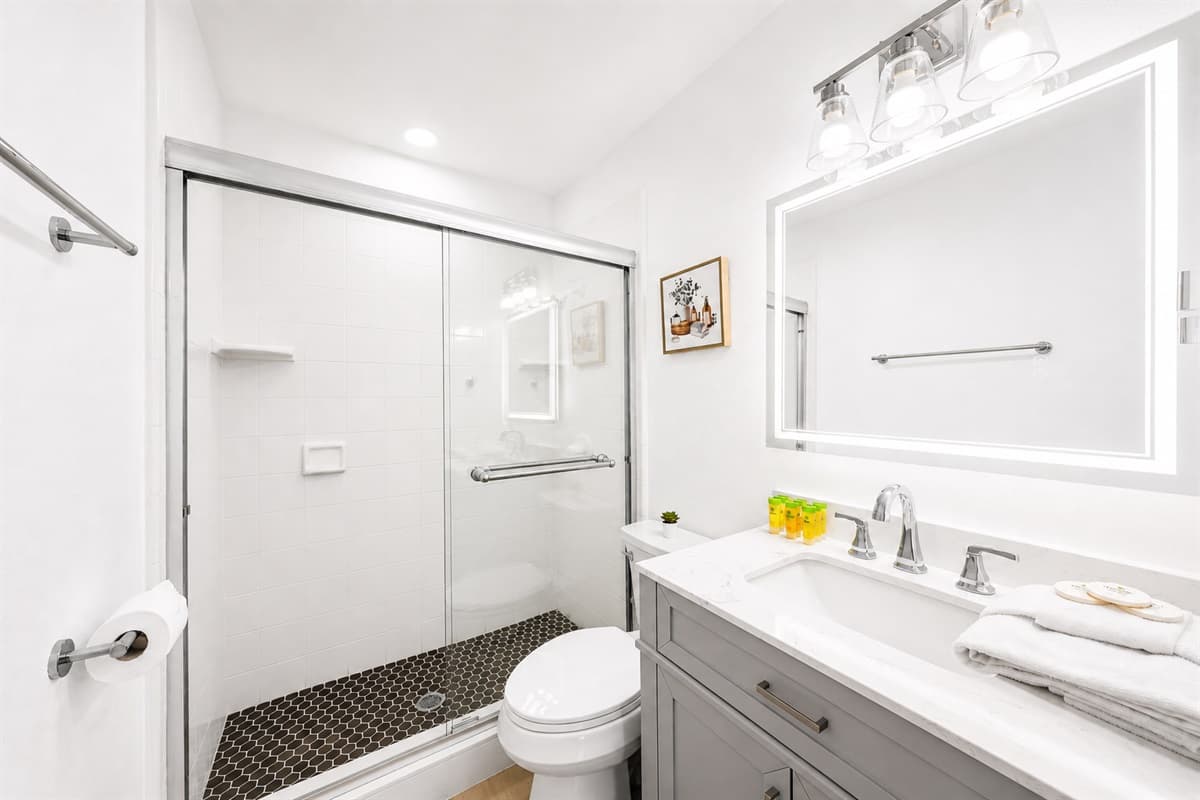 Contemporary guest bathroom with glass shower doors, modern fixtures, and spacious vanity.