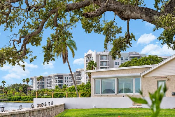 Shade of the old oak, sun on the water. Oak branches frame the house with the bay and waterfront buildings nearby. Classic Florida scenery right outside.