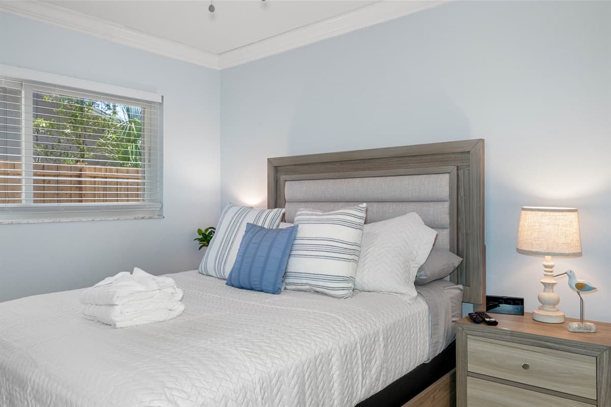 This inviting space features a cozy queen-size bed, complete with a plush mattress and soft, high-quality linens that promise comfort and relaxation.