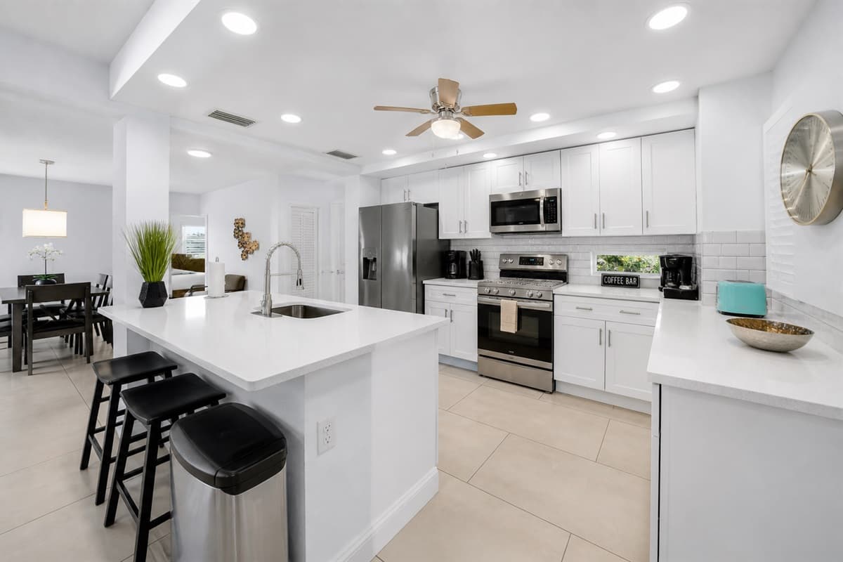 Fully equipped kitchen featuring stainless steel appliances, large island, and open dining flow.
