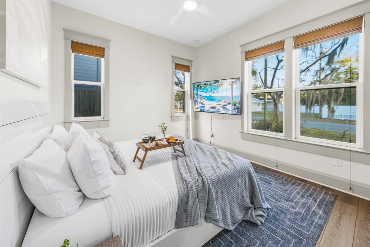 Wake up surrounded by nature! This dreamy bedroom features three large windows with a stunning panoramic view of Seminole Heights' lush oak tree canopy. Crisp white bedding, soft light — pure Florida bliss in a brand-new home.