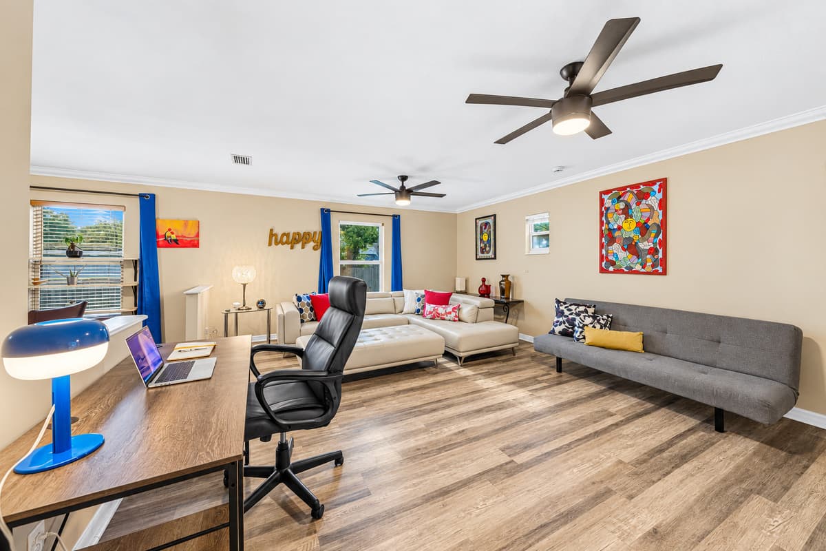 Spacious lounge with workspace setup, large sectional, and bright windows—perfect for both work and relaxation.