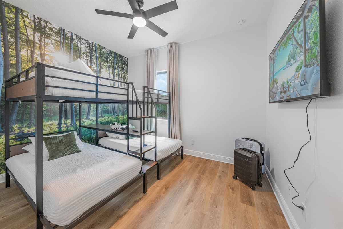 Spacious bunk room with multiple beds, TV, and large windows bringing in natural light.