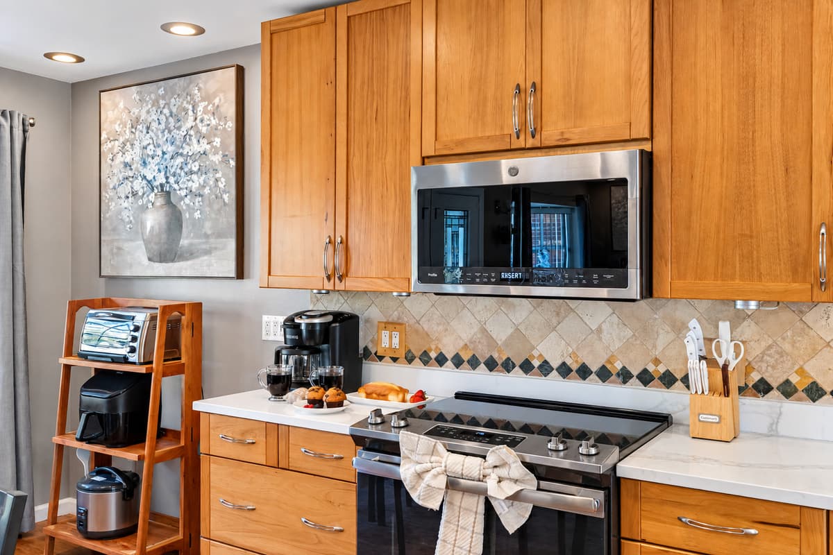 The tile backsplash with diamond accents adds a timeless detail, perfectly complementing the sleek modern finishes throughout the kitchen.