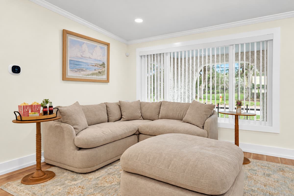 Sink into the den sectional. A deep sectional and ottoman with natural light and coastal art. A calm space away from the main living room.