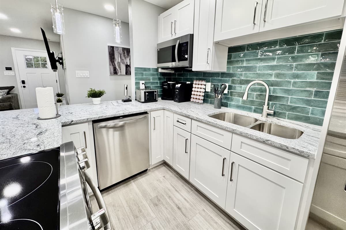 The sleek, polished countertops provide ample space for meal prep, while the thoughtfully arranged cabinetry is stocked with all the essentials, from pots and pans to baking sheets and cooking utensils.