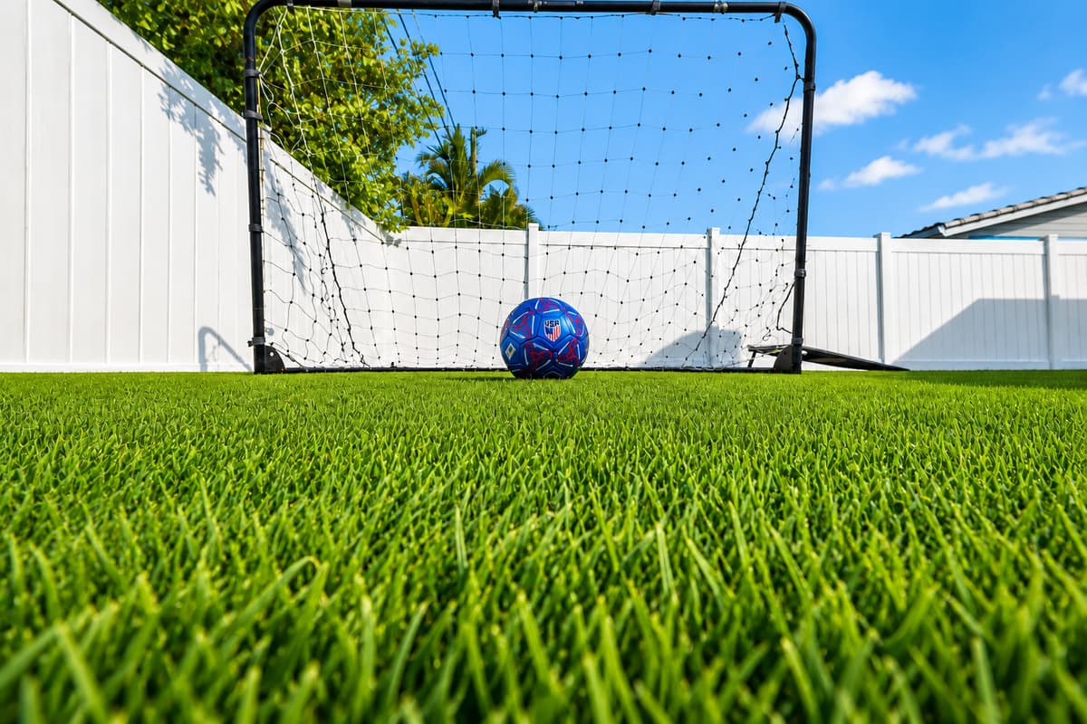 Backyard soccer goal setup with lush artificial turf, perfect for kids and outdoor fun.