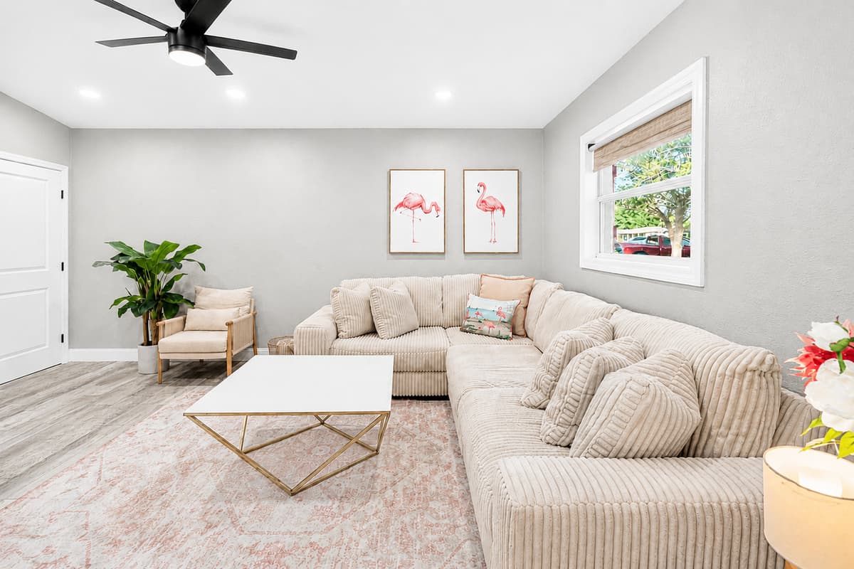 Bright living space with ample seating, neutral color palette, and open floor plan leading to adjacent rooms.