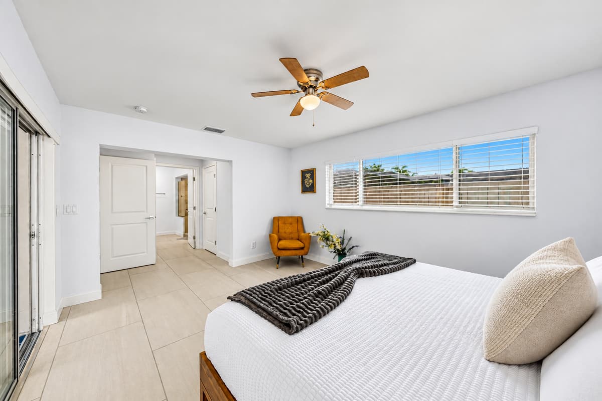 Spacious bedroom retreat with minimalist design, ceiling fan, and calming neutral tones.