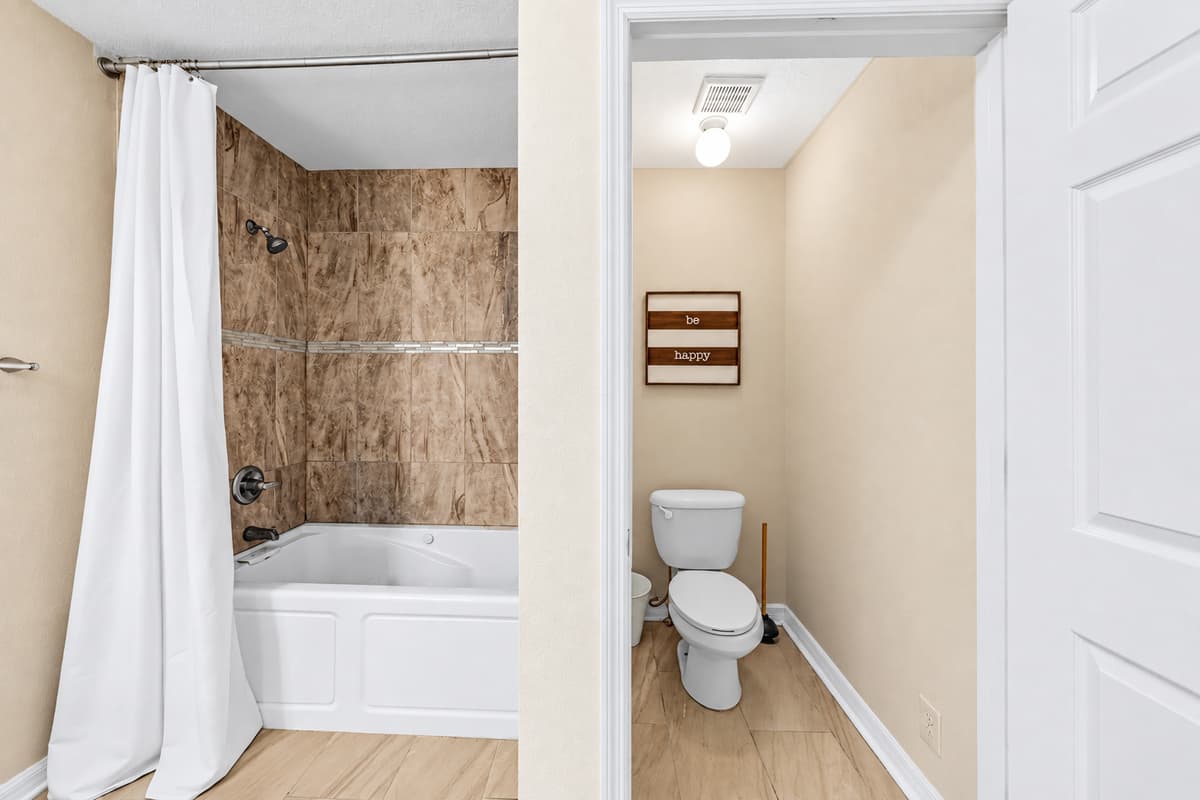 Clean and functional bathroom featuring a tub/shower combo and private toilet area.