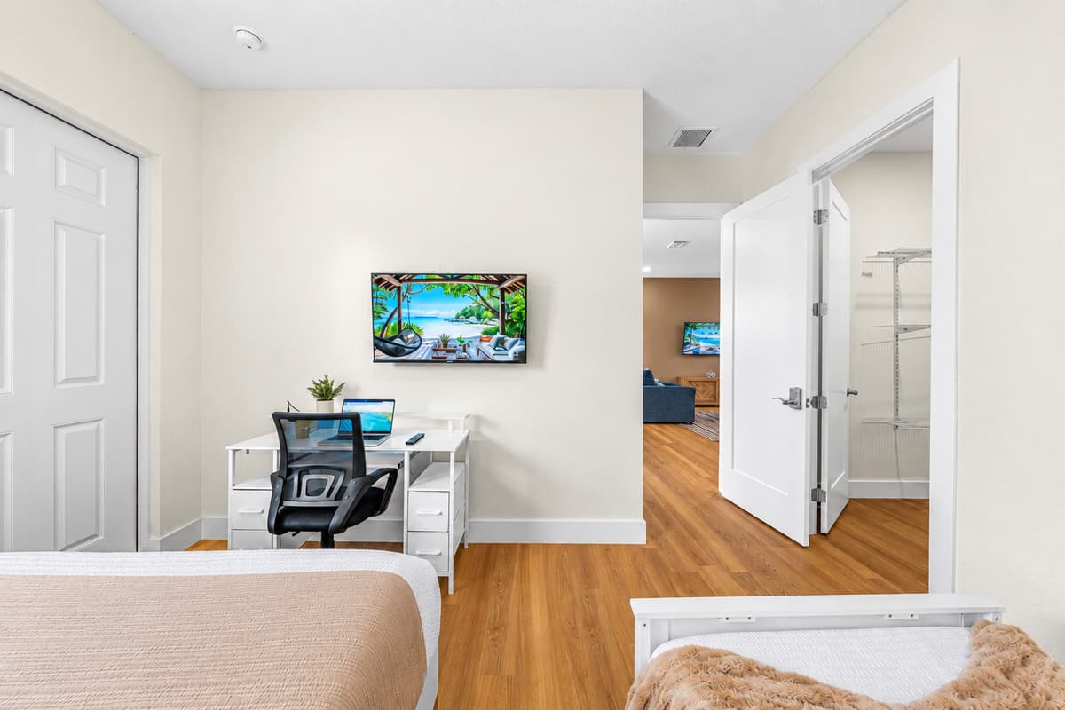 Work desk, Smart TV, and quiet when you need it. A dedicated desk faces a wall-mounted Smart TV, with the bed close by. Close the door for a focused call, open it to rejoin the group in the living room a few steps away.