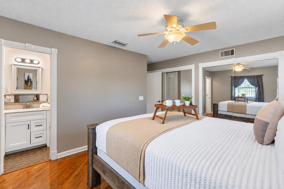 This bedroom offers a calming atmosphere with neutral tones, a ceiling fan, and direct access to its own ensuite bathroom.