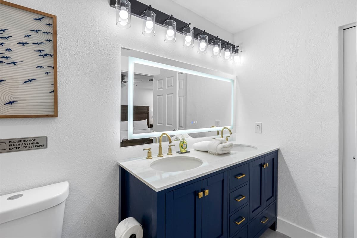 Bedroom 1 - Ensuite: Indulge in spa-like luxury with this beautifully designed bathroom featuring a dual-sink vanity, LED mirror, and rainfall shower surrounded by marble-style tile.