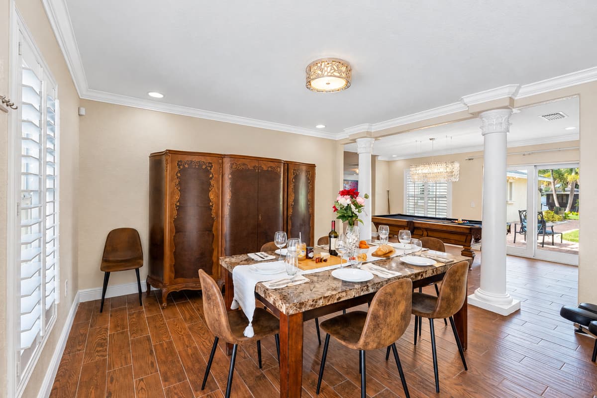 Natural light pours through plantation shutters, illuminating the beautifully set table and creating a welcoming atmosphere.