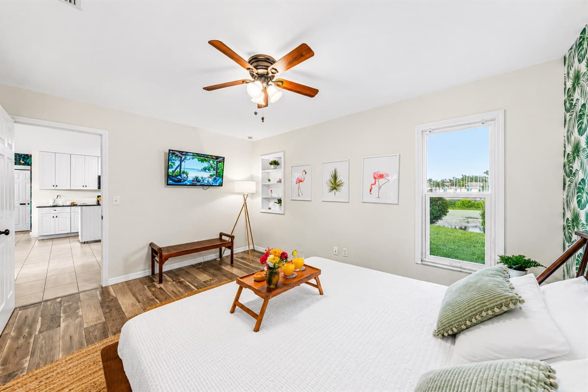 Spacious bedroom featuring a king bed, wall-mounted TV, and relaxing seating area.