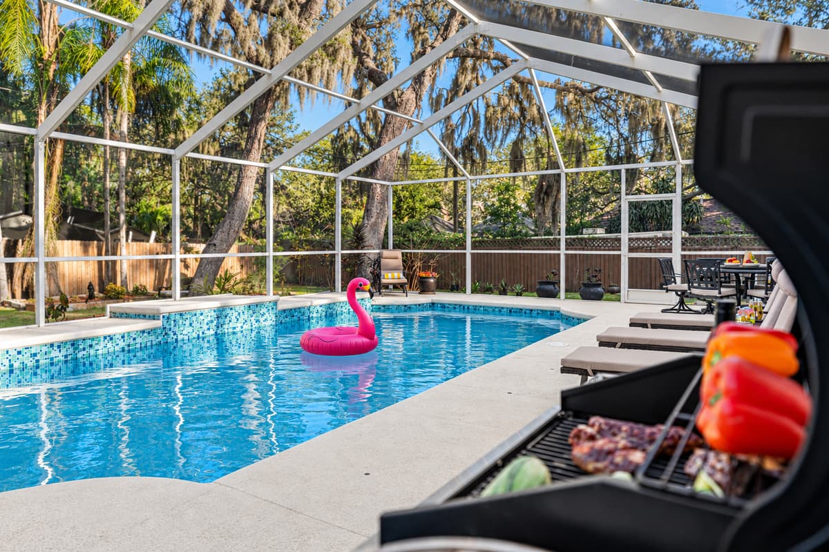 Take in the serene backyard setting featuring a crystal-clear private pool, screened enclosure, and peaceful wooded views for ultimate relaxation.